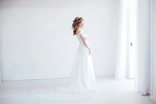 Nevěsta ve svatebních šatech v bílém pokoji — Stock fotografie