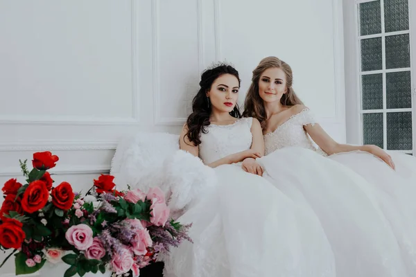 Porträt zweier junger Frauen in Brautkleidern im weißen Saal — Stockfoto