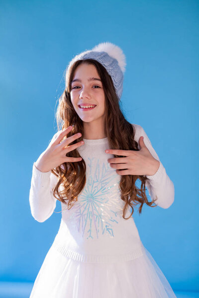 Beautiful fashionable girl in winter snow cap blue background
