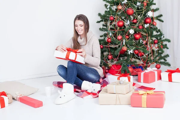 The girl looks Christmas gifts at the Christmas tree — Stock Photo, Image
