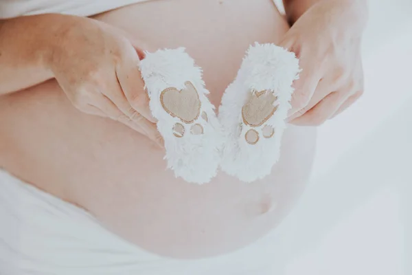 Magen på en gravid kvinna och baby saker strumpor 1 — Stockfoto