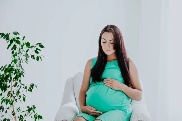 分娩前怀孕的妇女坐在白色的沙发上 — 图库照片