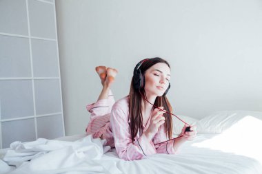 esmer pembe pijama yatağa kulaklık ile müzik dinlemek