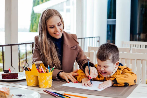 Мама помогает сыну рисовать цветные карандаши — стоковое фото