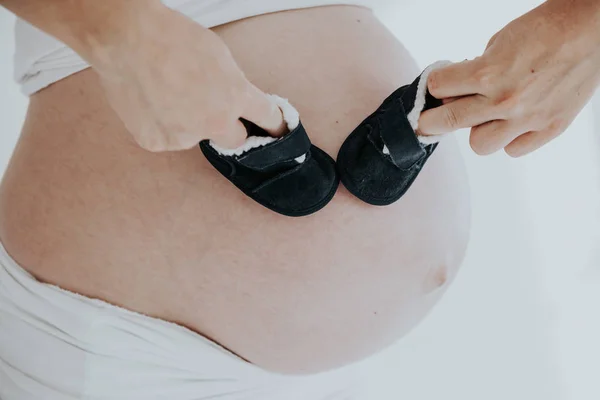 The stomach of a pregnant woman and baby stuff socks — Stock Photo, Image