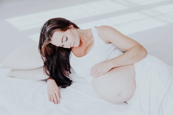 Uma mulher grávida está deitada na cama esperando o nascimento de uma criança — Fotografia de Stock