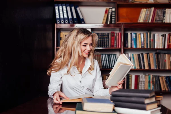 La chica sentada en la biblioteca leyendo libros se está preparando para el examen — Foto de Stock