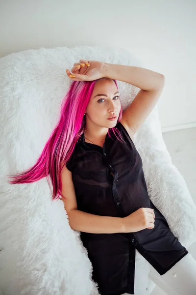 Дівчина з рожевим волоссям сидить у білому кріслі — стокове фото