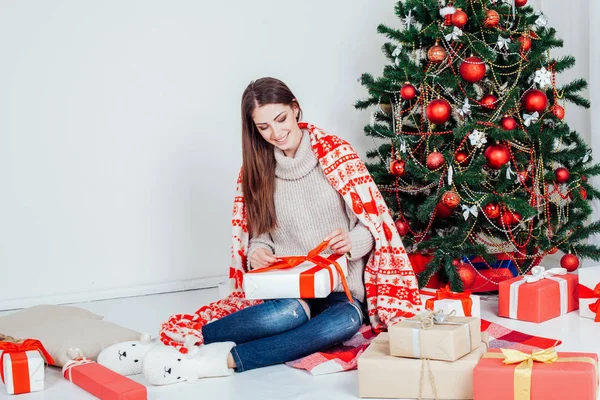 The girl looks Christmas gifts at the Christmas tree — Stock Photo, Image