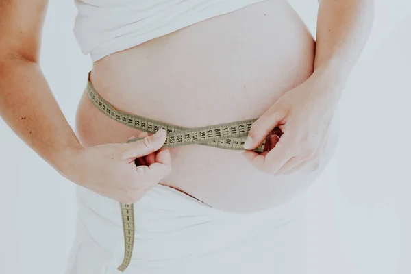 Der Magen einer Schwangeren und ein Maßband — Stockfoto