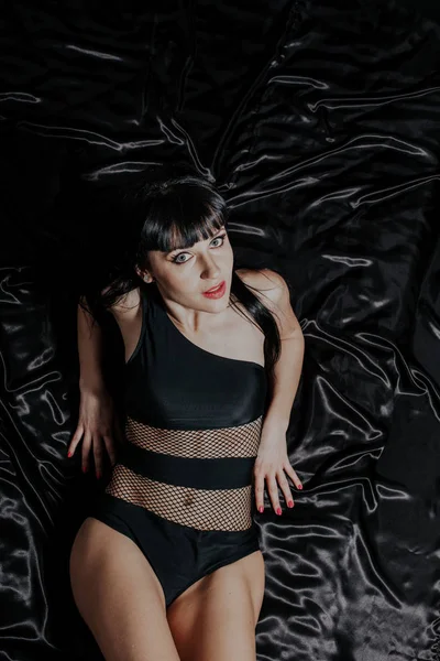 Menina sexy em roupa interior preta encontra-se na cama de seda — Fotografia de Stock