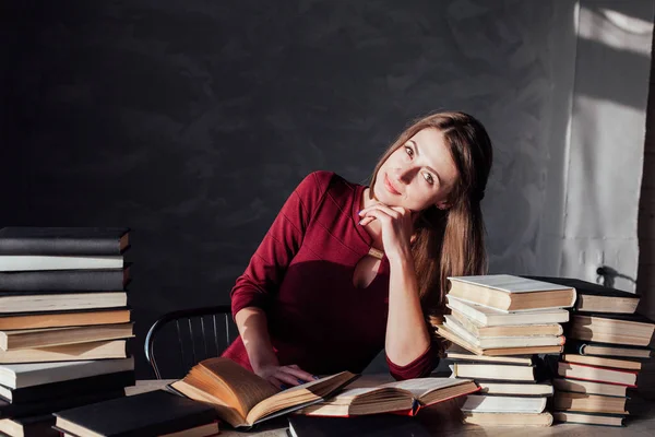 La fille assise à la table lisant beaucoup de livres — Photo