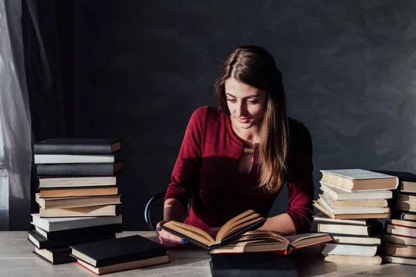 A menina sentada à mesa lendo um monte de livros — Fotografia de Stock