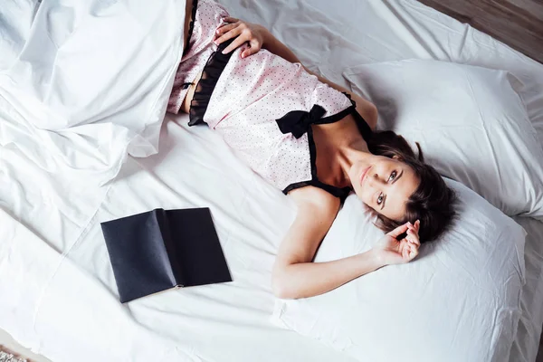 ベッドの前に本をベッドに寝そべっているパジャマ姿の女の子 — ストック写真
