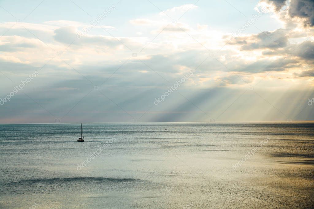 yacht in the sea rays from clouds landscape