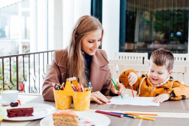 Anne ve oğlu restoranda kalemler yemeden önce boyalı