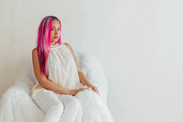 The girl with the pink hair is sitting in a white armchair — Stock Photo, Image