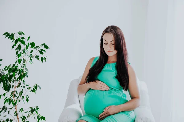 Une femme enceinte avant l'accouchement est assise sur un canapé blanc — Photo