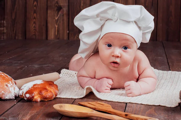 Baby Cook leży na mące chleb stołowy — Zdjęcie stockowe