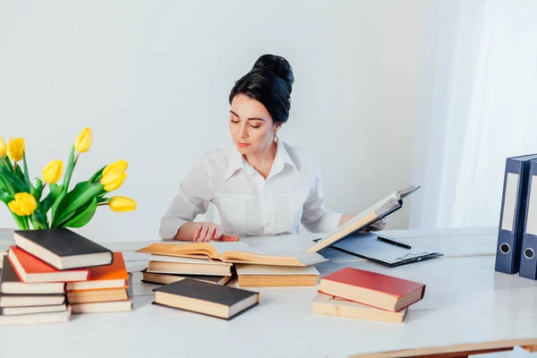 Brunetka Kobieta w garniturze czyta książki w biurze — Zdjęcie stockowe