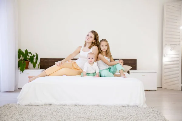 Tres hermanas en la cama en el dormitorio por la mañana — Foto de Stock