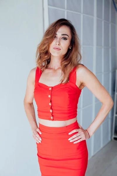 Ritratto di una bella donna alla moda in un vestito rosso in una stanza bianca — Foto Stock