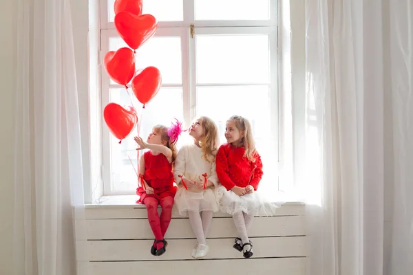 Τρία κορίτσια με κόκκινα μπαλόνια σε σχήμα καρδιάς στις διακοπές — Φωτογραφία Αρχείου
