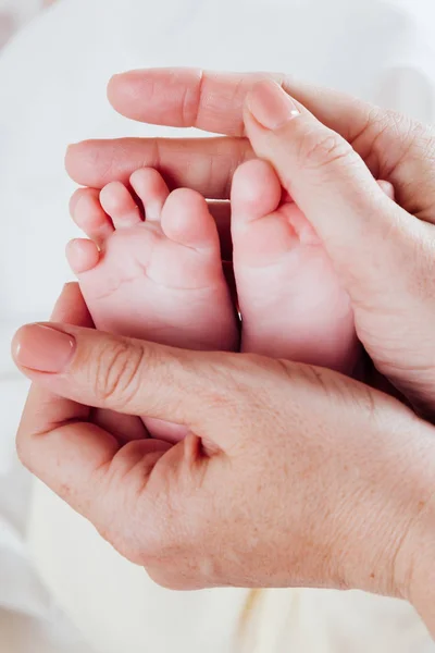 Moms hands hold the feet toes kids – stockfoto