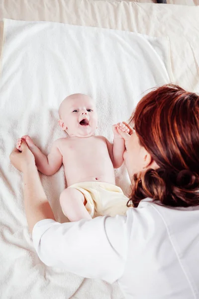 Den lille guttens mor som gjør massasje hender og bein – stockfoto