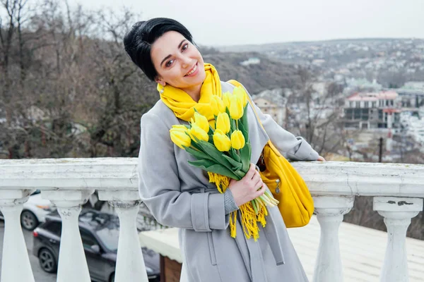 Porträt einer Brünetten in Mänteln mit gelben Tulpen — Stockfoto