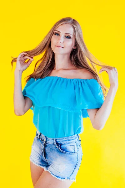Vacker blond flicka på en gul bakgrund i blå klänning — Stockfoto