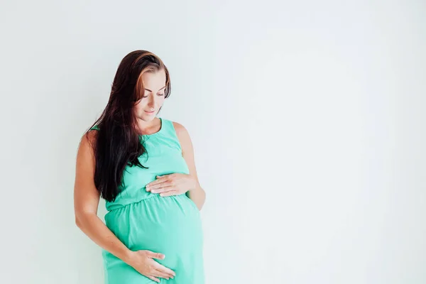 一个怀孕的女人站在窗户旁边的墙上 — 图库照片