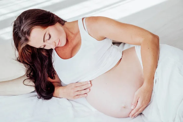 Těhotná žena leží v posteli, čekání na narození dítěte — Stock fotografie