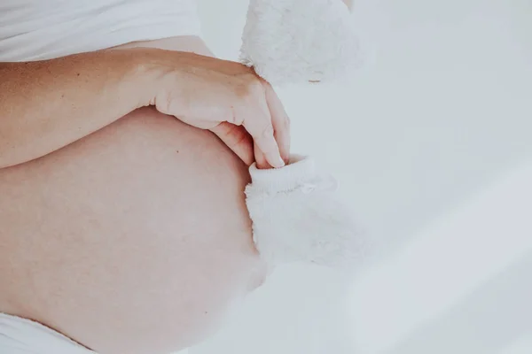 Der Bauch einer schwangeren Frau und Babysocken 1 — Stockfoto