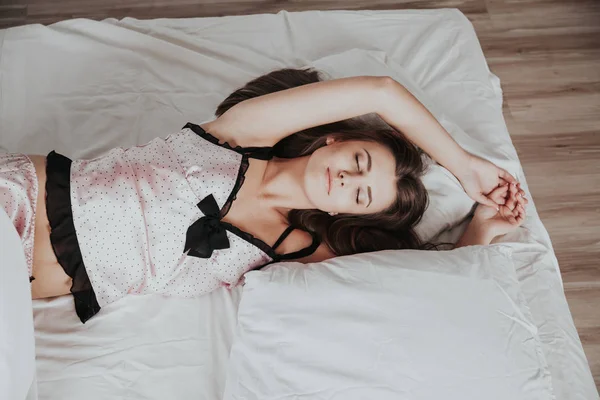 パジャマを着た美しい女の子がリネンのベッドで寝ています — ストック写真