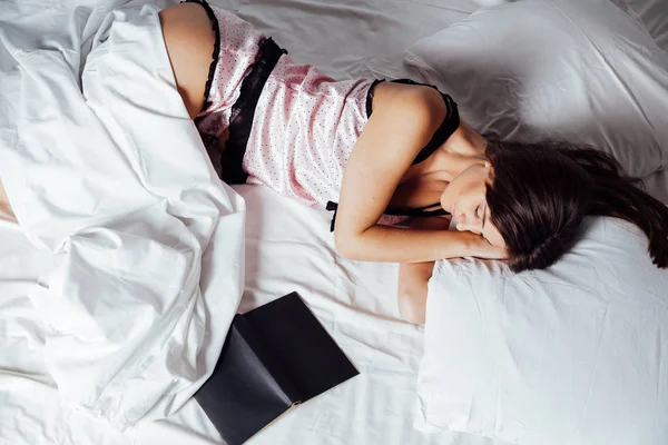 Meisje in pyjama liggend op het bed met een boek voor bed — Stockfoto