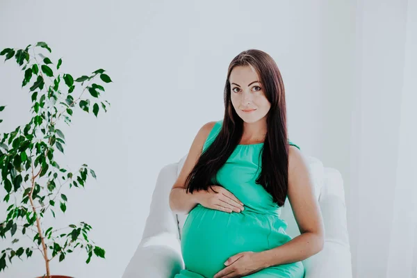 分娩前怀孕的妇女坐在白色的沙发上 — 图库照片