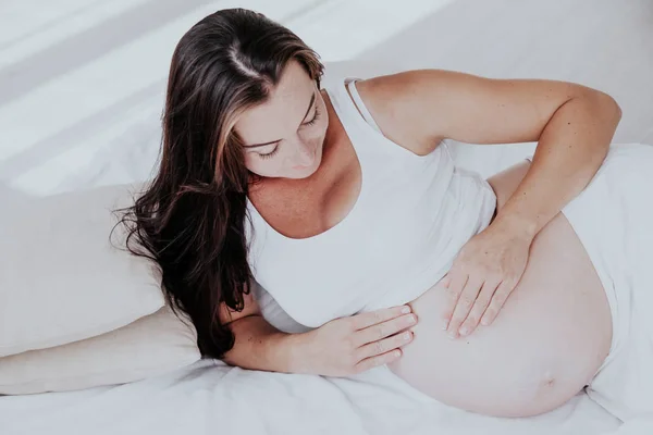 Беременная женщина лежит в постели и ждет рождения ребенка — стоковое фото