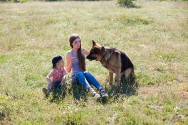 Alman çoban köpeğiyle yürüyüşe çıkmış bir kadın.