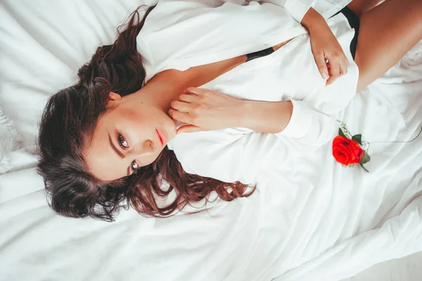 Κορίτσι στο εσωρούχων ξαπλωμένος σε ένα κρεβάτι με ένα τριαντάφυλλο — Φωτογραφία Αρχείου