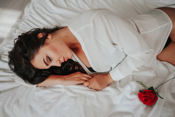 Chica en lencería acostada en una cama con una rosa —  Fotos de Stock