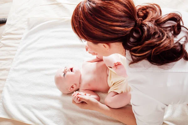 Den lille guttens mor som gjør massasje hender og bein – stockfoto