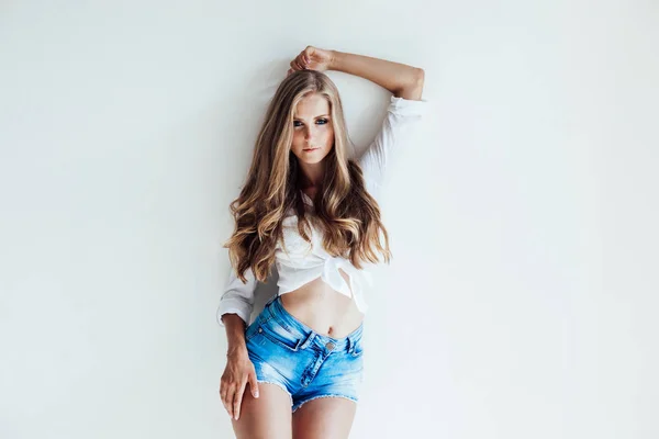 Blondes Mädchen mit blauen Augen in Shorts auf weißem Hintergrund — Stockfoto