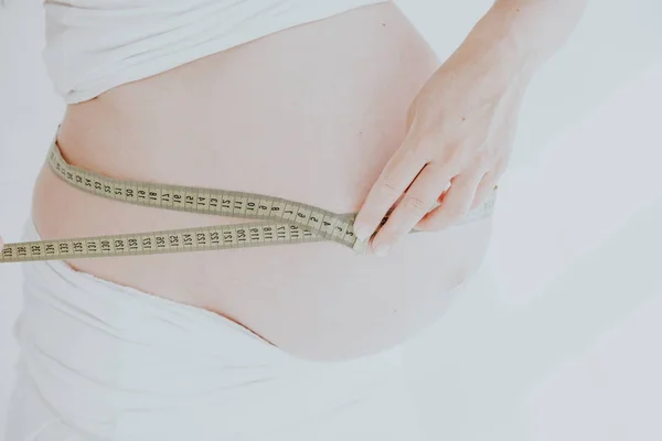 Der Magen einer Schwangeren und ein Maßband — Stockfoto