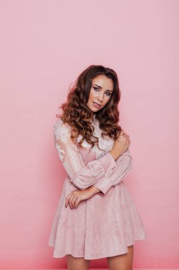 Pembe elbiseli, saçları kıvırcık güzel bir kadının portresi.