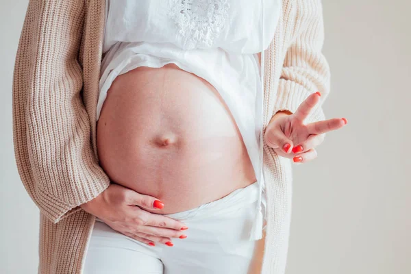 De maag van de hand van een zwangere vrouw toont twee vingers — Stockfoto