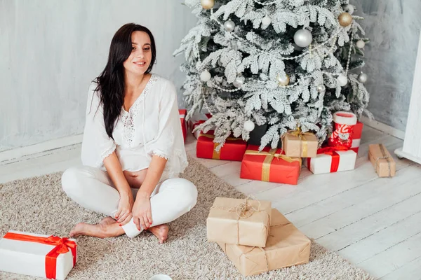 Beautiful pregnant woman at the Christmas tree with gifts for the new year — Stock Photo, Image
