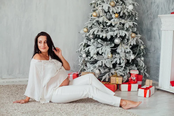 A pregnant woman sitting in the room with the Christmas tree — Stock Photo, Image