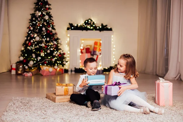 Den lilla pojken och flickan öppna julklappar julgran nyår Eve familj fest — Stockfoto