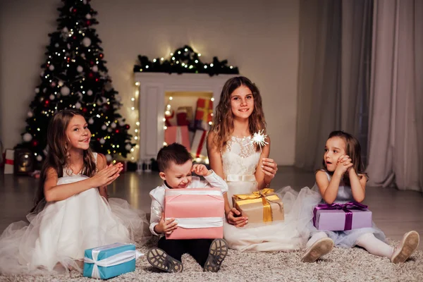 O menino e três meninas abrir presentes árvore de Natal ano novo grinalda — Fotografia de Stock